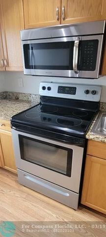 a view of a kitchen with kitchen island granite countertop a sink a counter top space and cabinets