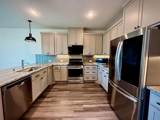 a kitchen with granite countertop a refrigerator stove and sink