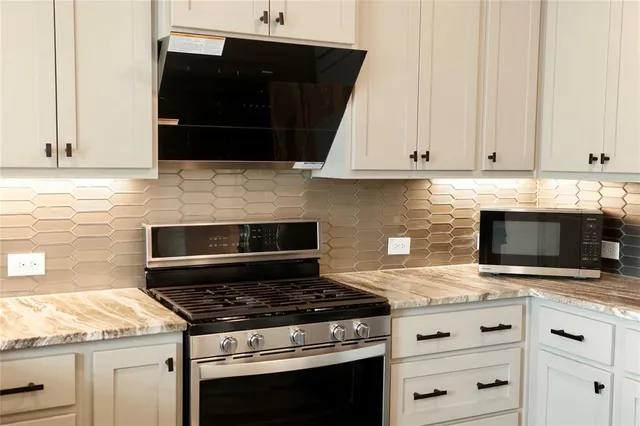 a kitchen with granite countertop white cabinets and stainless steel appliances