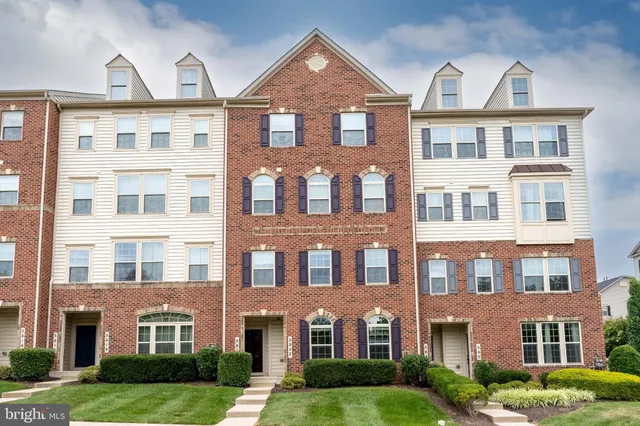 a front view of a residential apartment building with yard and green space
