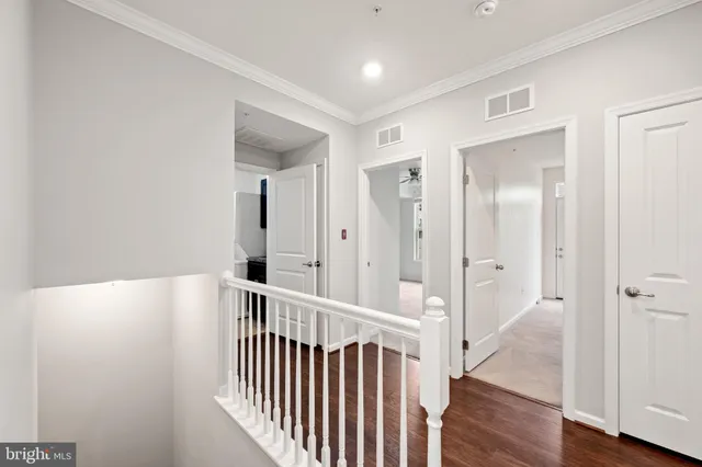 a view of a hallway with wooden floor and a bathroom