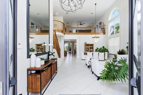 a hallway with a lots of white furniture and potted plants