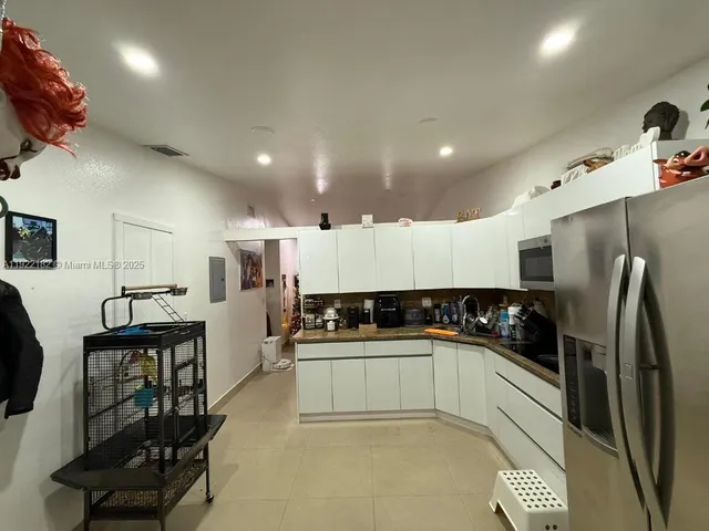 a kitchen with stainless steel appliances a sink a stove a refrigerator cabinets and a chairs