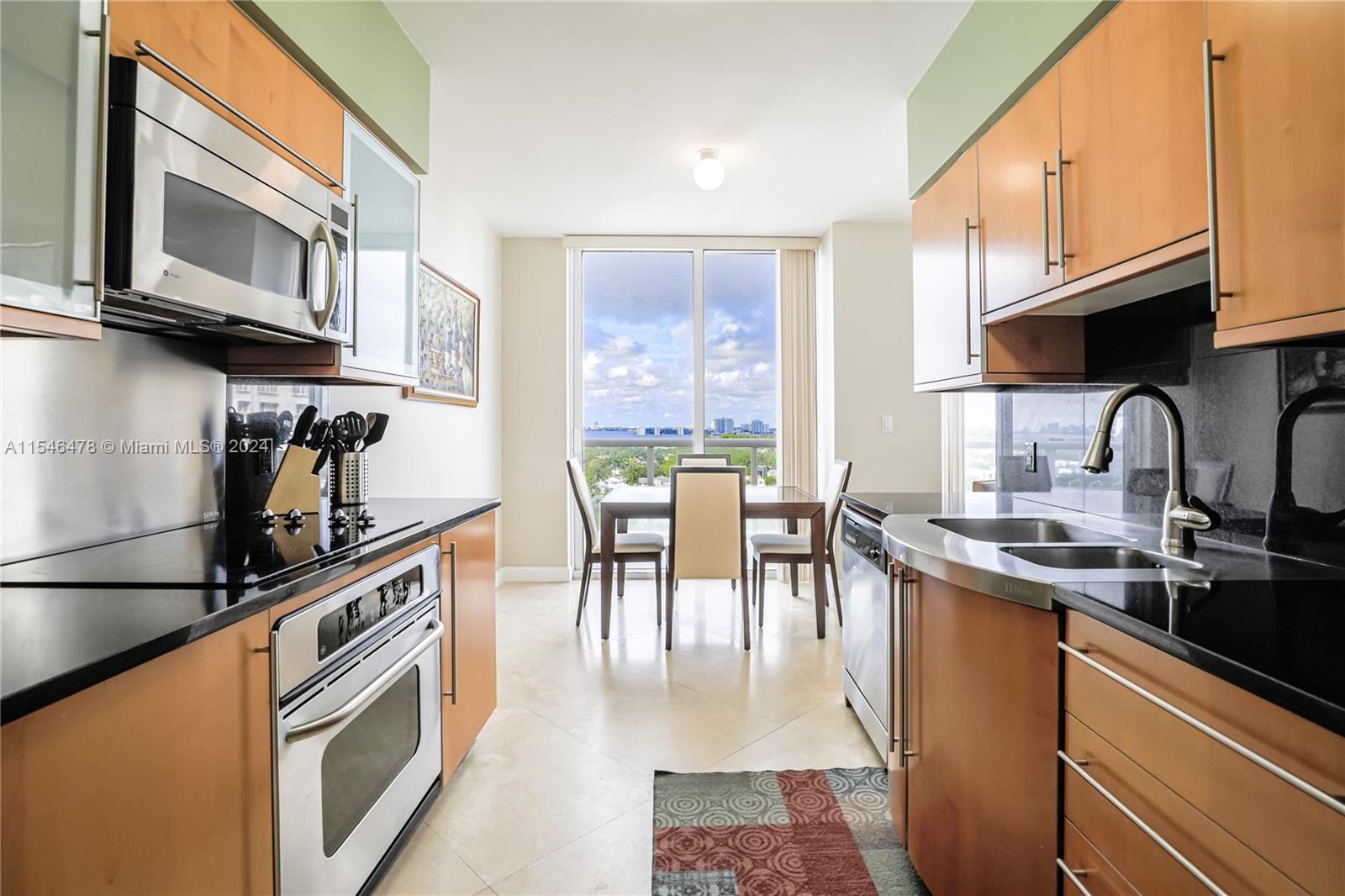 6365 Collins Avenue, Unit 1408 Miami Beach, FL 33141 - Photo 24 of 37 a kitchen with stainless steel appliances granite countertop a stove top oven a sink a dining table and chairs