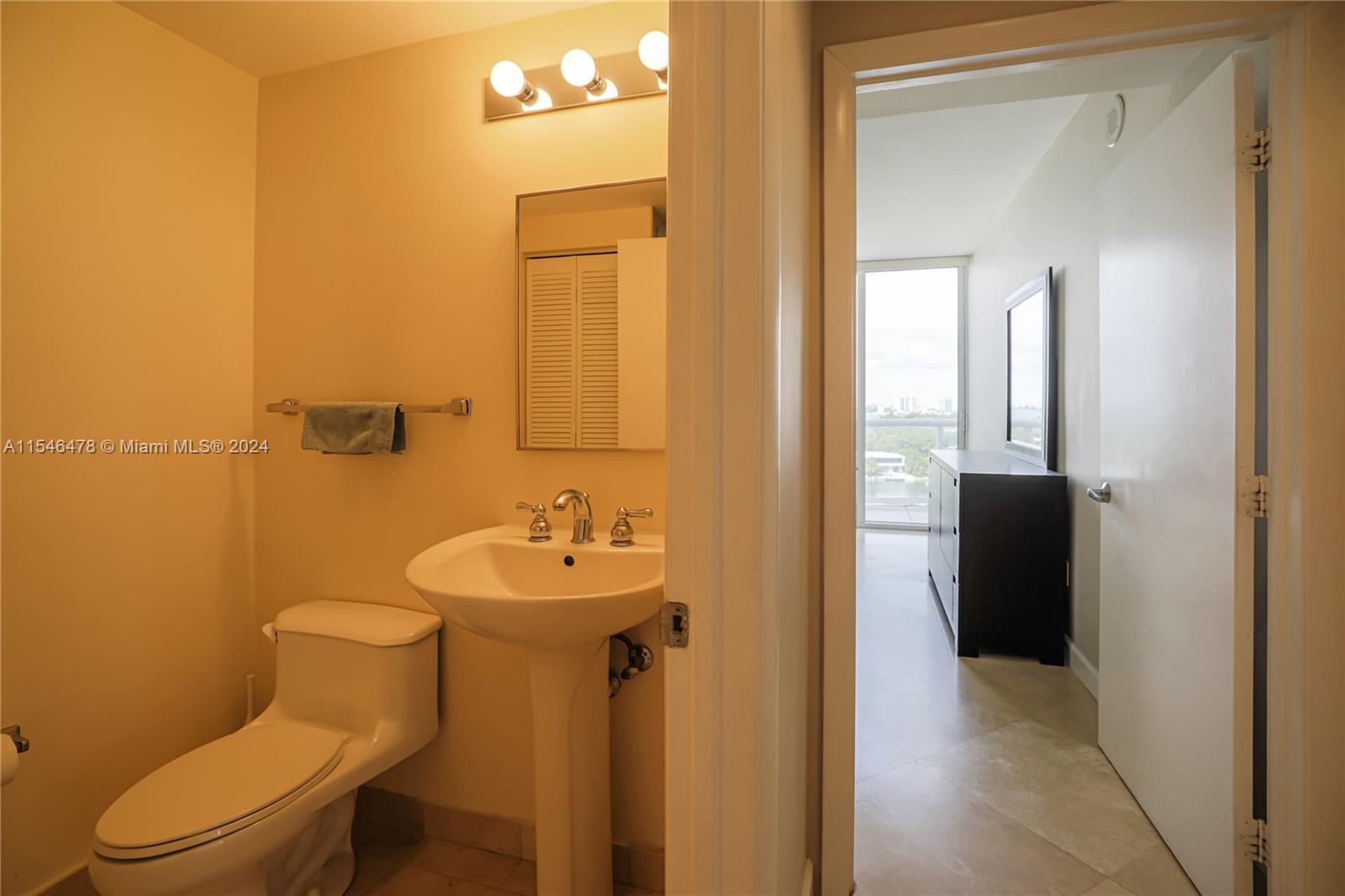 6365 Collins Avenue, Unit 1408 Miami Beach, FL 33141 - Photo 33 of 37 a bathroom with a toilet sink and mirror