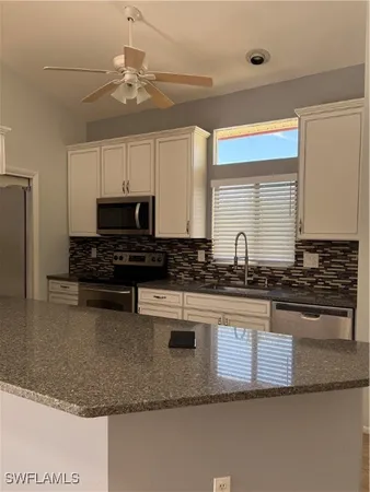 a kitchen with stainless steel appliances granite countertop a sink a stove a microwave a counter top space and cabinets