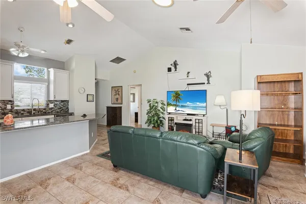 a living room with furniture a flat screen tv and kitchen view