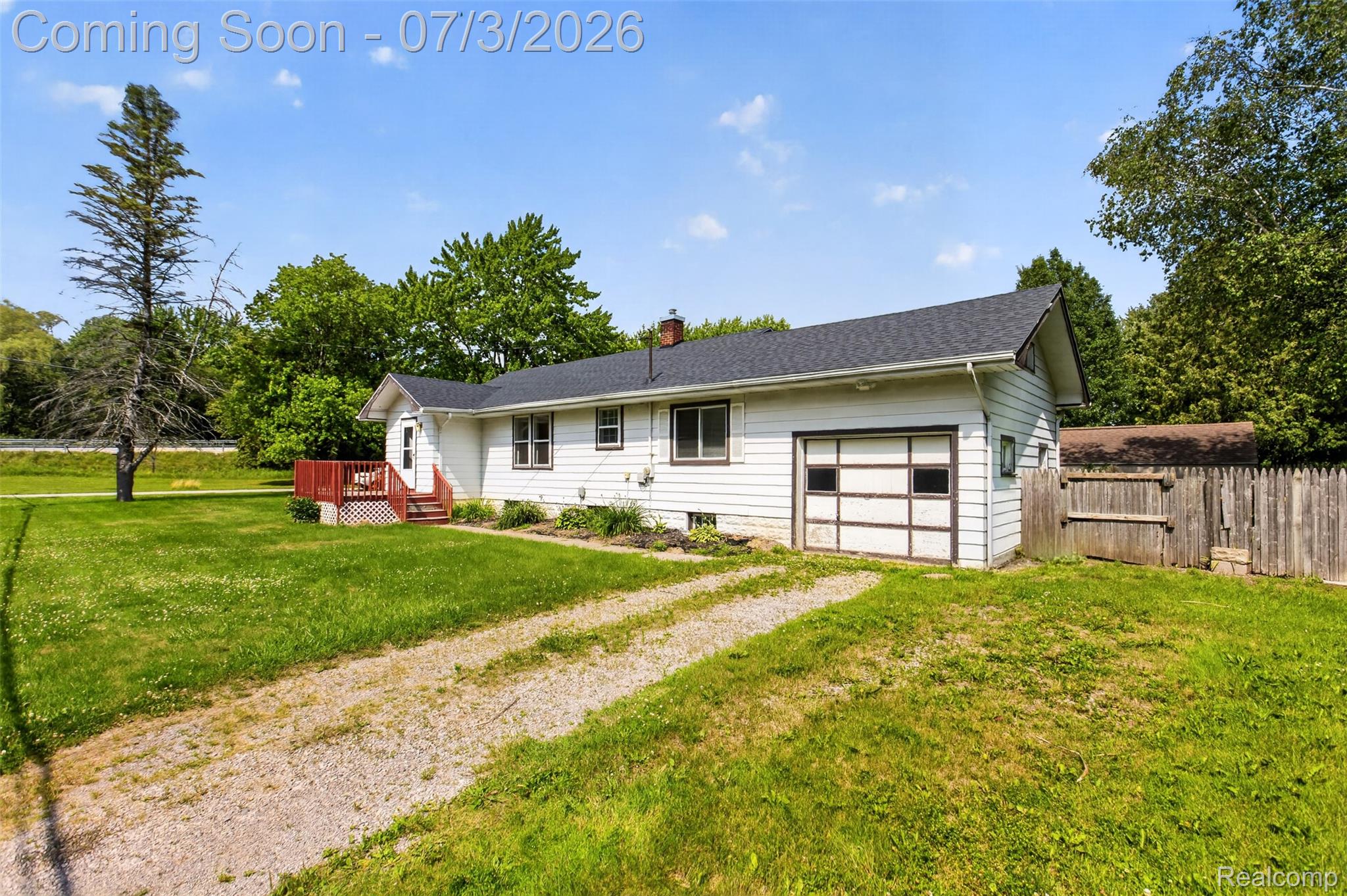 4322 Baker Road Bridgeport, MI 48722 - Photo 29 of 29 White siding exterior with a dark shingle roof, attached garage, and a red deck