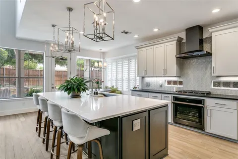 a kitchen with stainless steel appliances stove a dining table chairs and wooden floor