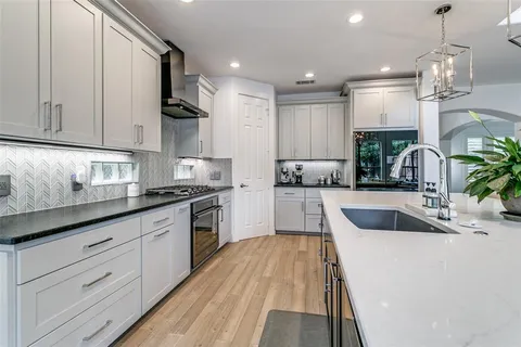 a kitchen with kitchen island granite countertop a sink stainless steel appliances and cabinets