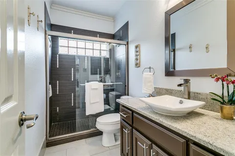 a bathroom with a granite countertop sink a toilet a mirror and shower