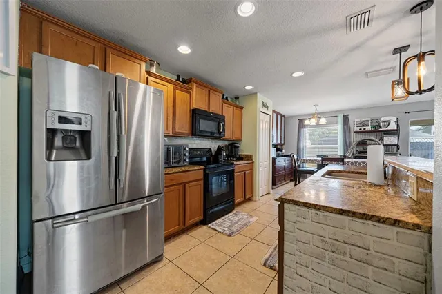a kitchen with stainless steel appliances granite countertop a refrigerator a stove a sink and a microwave