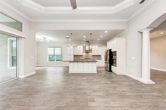 a view of a big room with wooden floor a ceiling fan and windows