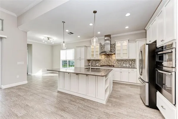 a kitchen with stainless steel appliances kitchen island granite countertop a stove a refrigerator a sink a oven and a wooden floor