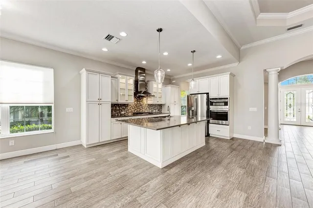 a kitchen with stainless steel appliances kitchen island wooden floors and white cabinets