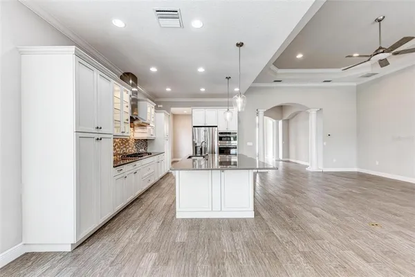 an empty room with wooden floor chandelier and windows