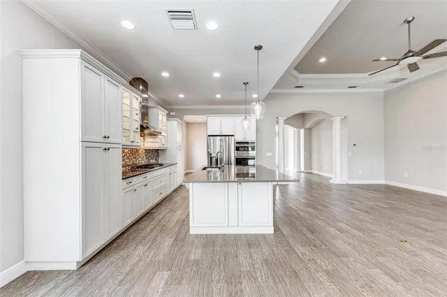 an empty room with wooden floor chandelier and windows