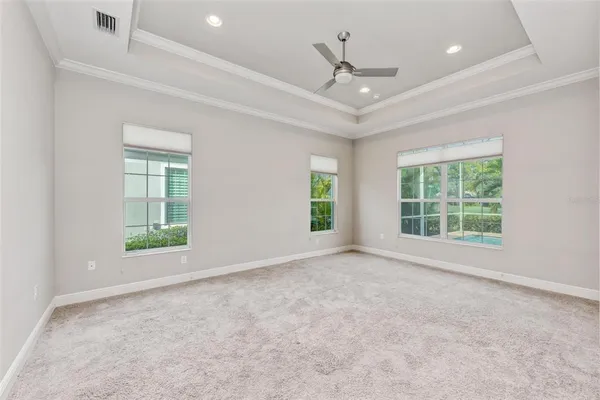 an empty room with windows and ceiling fan