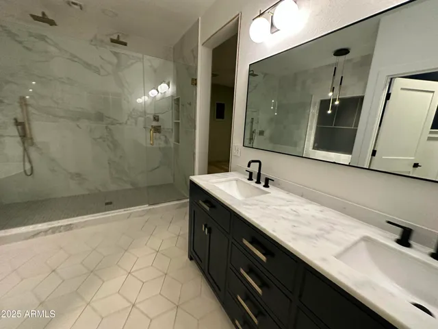 a bathroom with a granite countertop sink a mirror and a shower