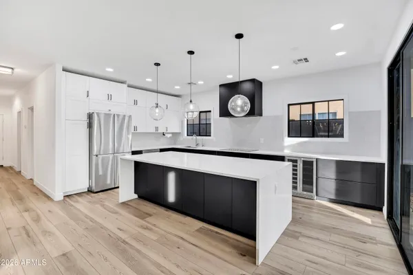 a large kitchen with a large center island wooden floor stainless steel appliances and cabinets
