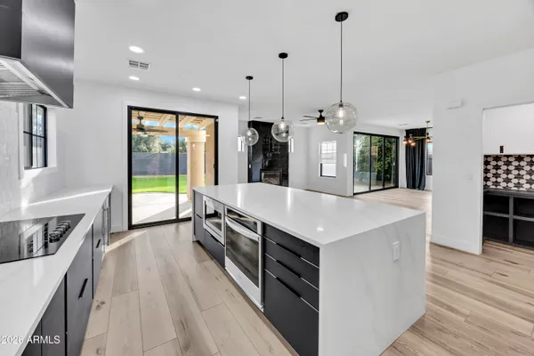 a kitchen with stainless steel appliances granite countertop a sink a stove and a wooden floors