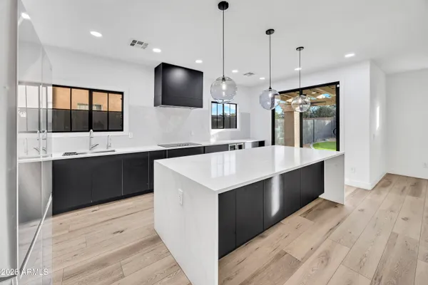 a large kitchen with a large counter top a sink stainless steel appliances and cabinets