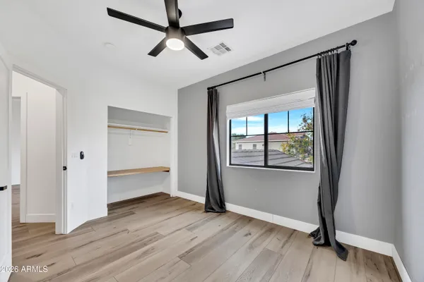 a view of empty room with wooden floor and fan