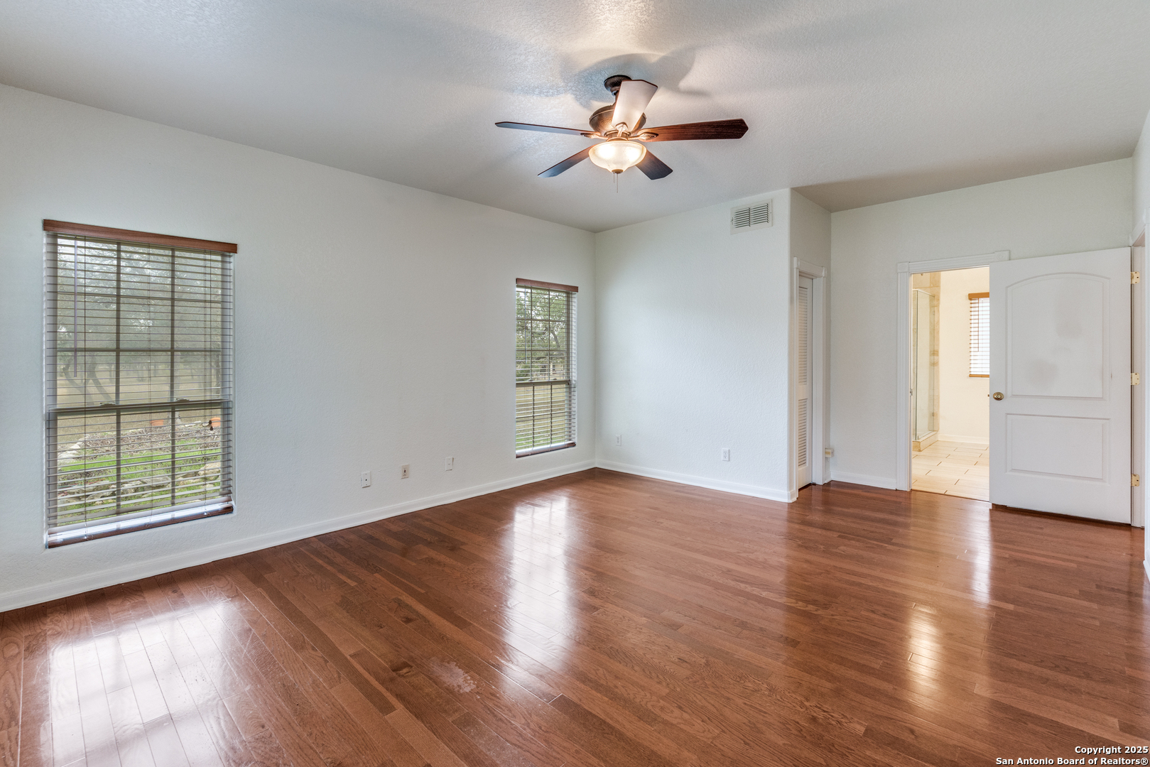 201 Yucca Canyon Spring Branch, TX 78070 - Photo 8 of 40 an empty room with wooden floor chandelier fan and windows