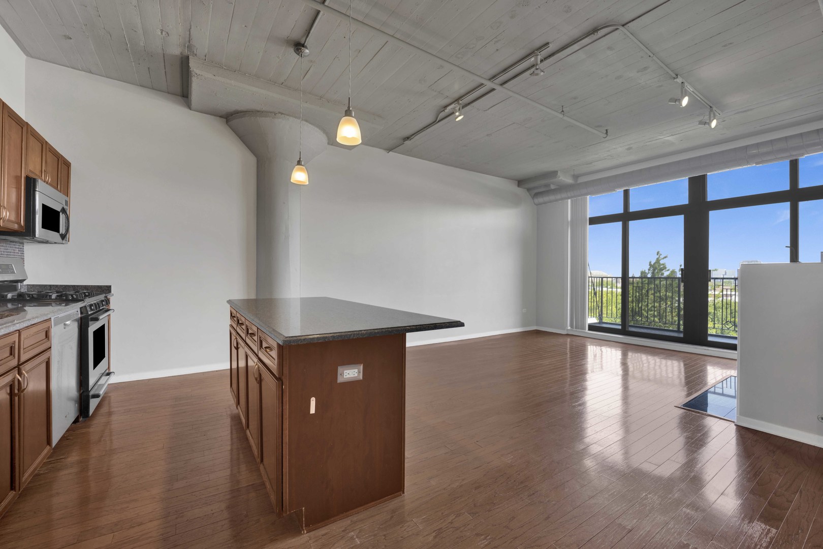 1525 South Sangamon Street, Unit 504 Chicago, IL 60608 - Photo 6 of 32 a kitchen with stainless steel appliances granite countertop a stove a refrigerator a sink with wooden cabinets and wooden floor