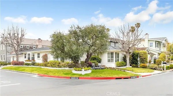 a view of yellow house with a big yard and plants