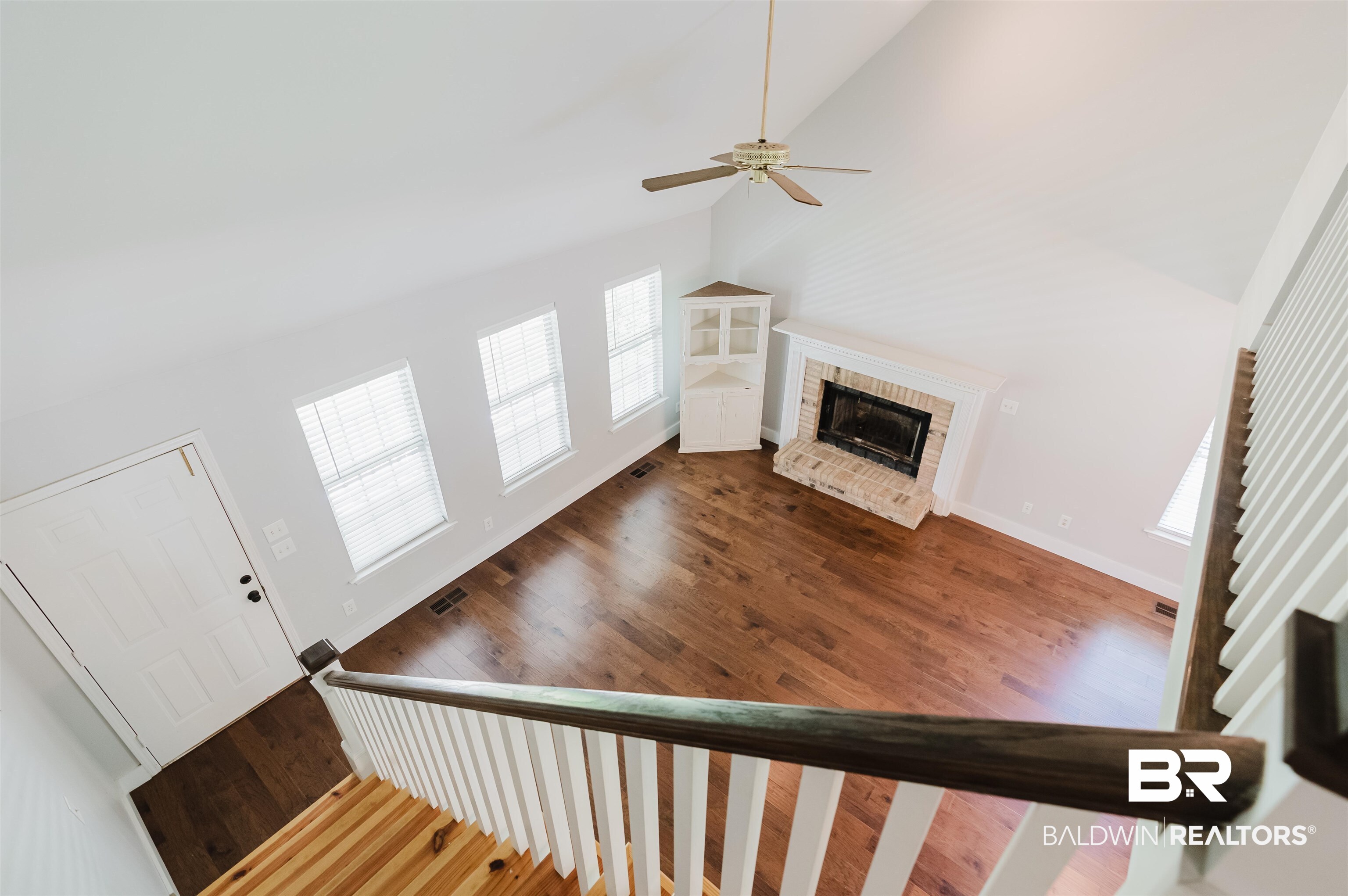 20460 Bishop Road Fairhope, AL 36532 - Photo 8 of 41 Staircase featuring lofted ceiling, a fireplace, ceiling fan, wood finished floors, and baseboards