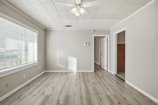 a view of an empty room with wooden floor and a window