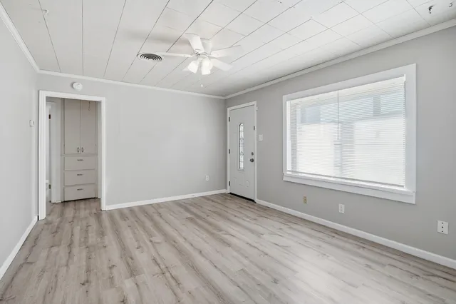 a view of an empty room with wooden floor and a window