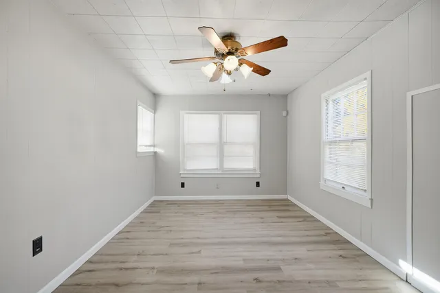 a view of an empty room with wooden floor and a window