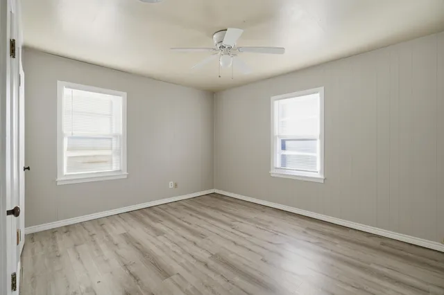 an empty room with wooden floor and windows