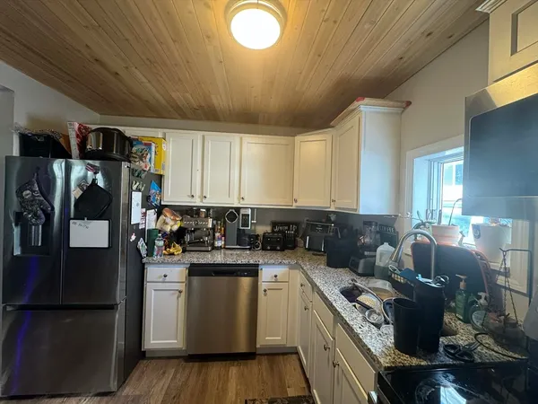a kitchen with stainless steel appliances granite countertop a stove a refrigerator a sink dishwasher and white cabinets with wooden floor