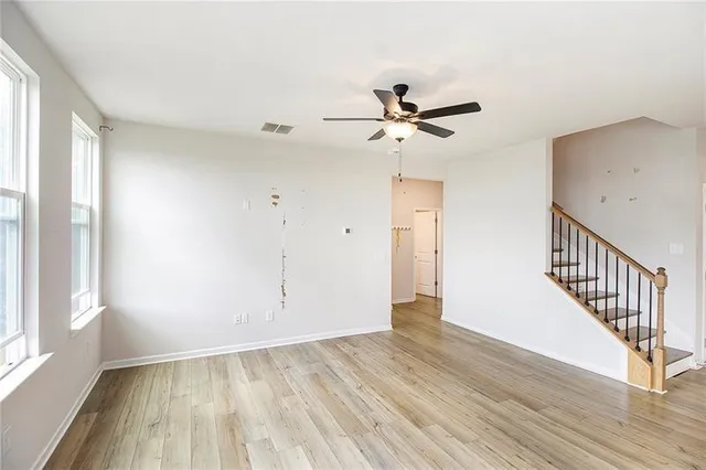 a view of empty room with wooden floor and fan