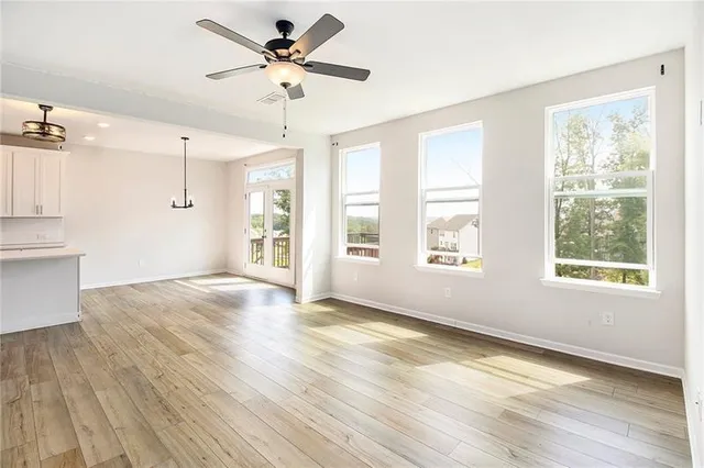 a view of an empty room with a window and wooden floor