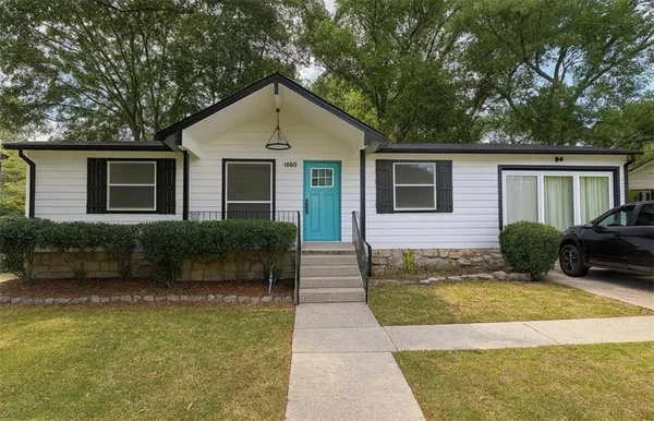 a view of a house with a small yard plants and large tree