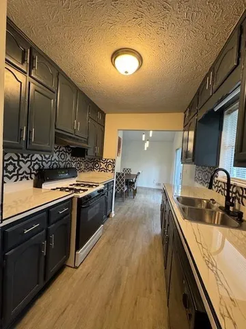 a kitchen with stainless steel appliances granite countertop a sink a stove and a wooden floors