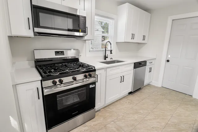 a kitchen with stainless steel appliances granite countertop white cabinets a stove top oven