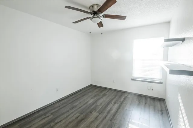 an empty room with a window and a ceiling fan