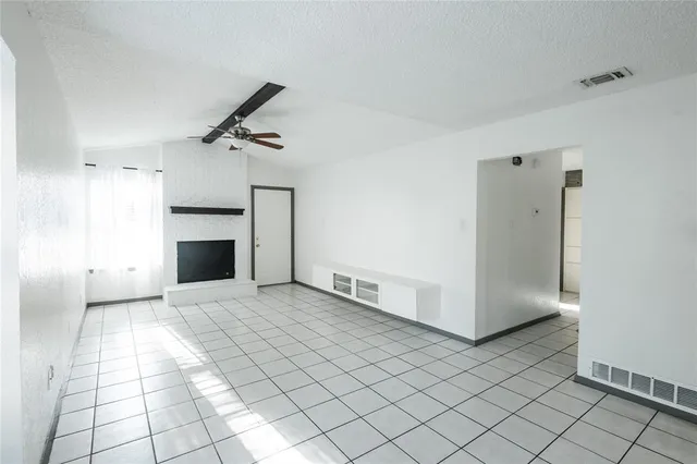 an empty room with windows and fireplace