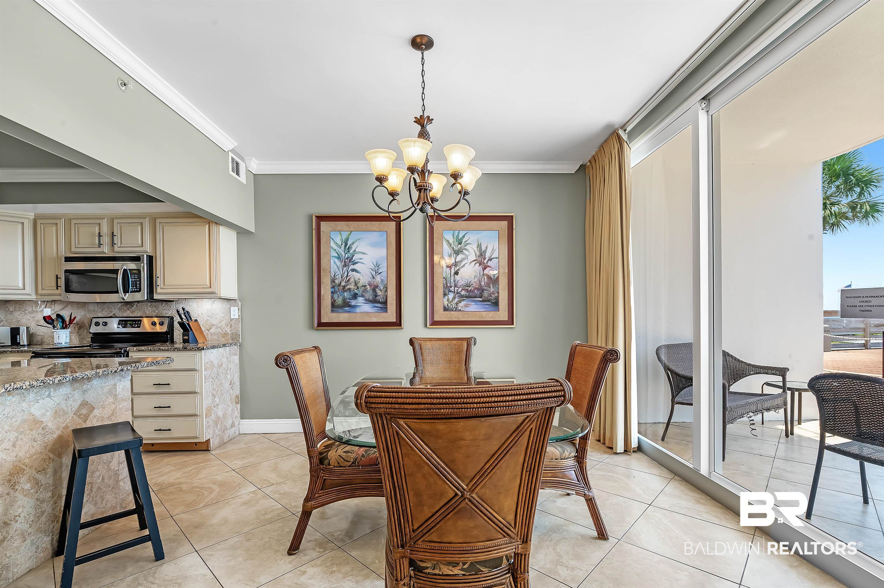 16287 Perdido Key Drive, Unit 105 Pensacola, FL 32507 - Photo 12 of 66 Dining area featuring a glass-top table, wicker chairs, and a bronze chandelier