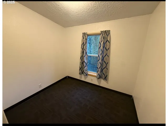 an empty room with wooden floor closet and windows