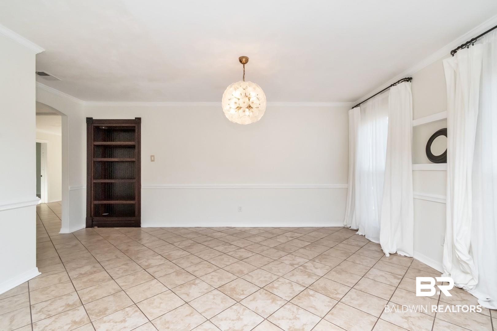1508 Ridgeland Road East Mobile, AL 36695 - Photo 6 of 45 Unfurnished room featuring light tile patterned floors, arched walkways, crown molding, built in shelves, and a chandelier