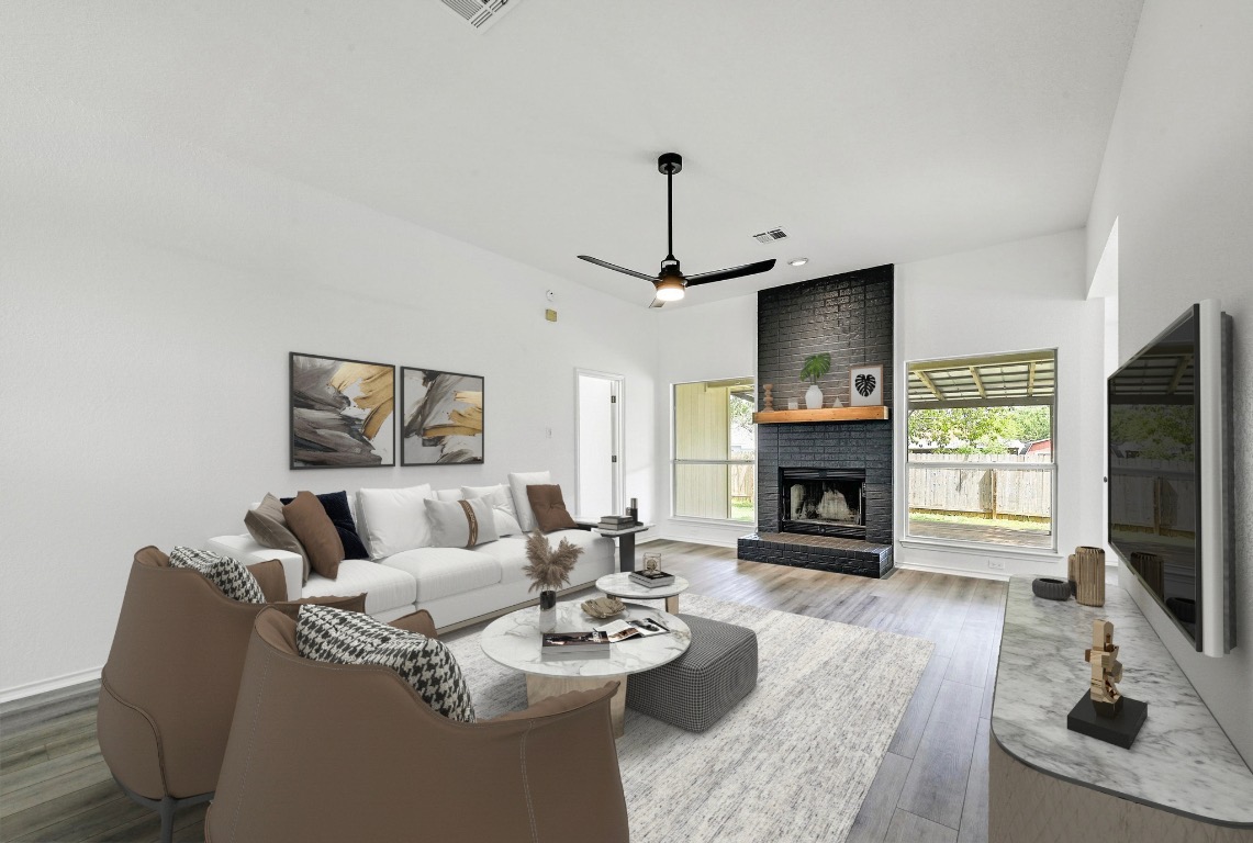 Living area with a fireplace, wood finished floors, and a ceiling fan