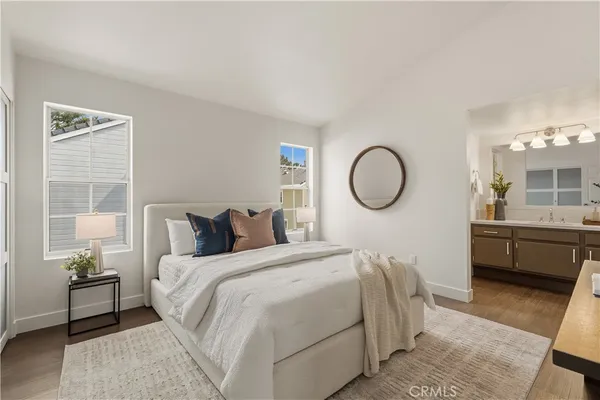 a bedroom with a bed a mirror and night stand with a window