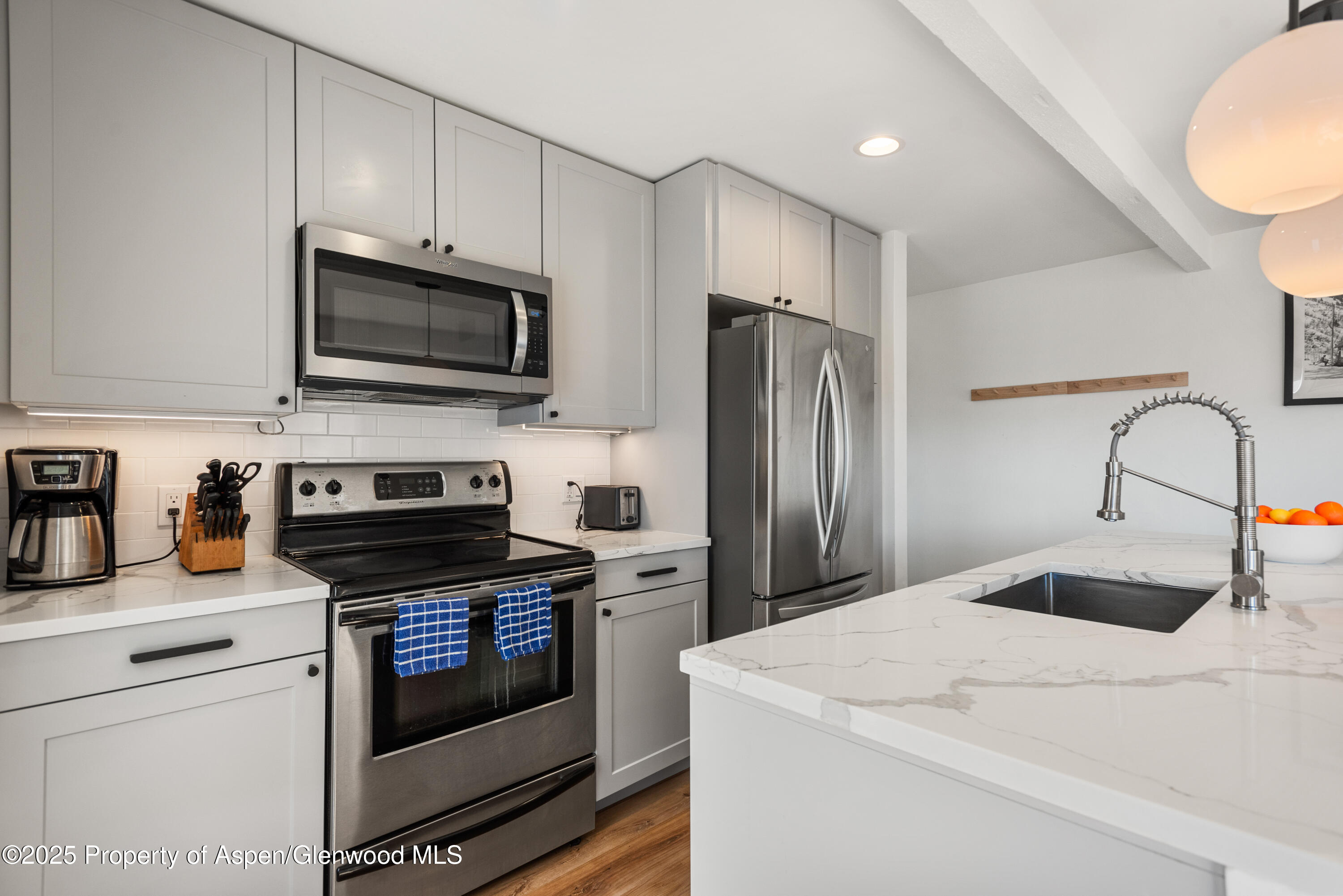 35 Upper Woodbridge Road, Unit 34CD Snowmass Village, CO 81615 - Photo 4 of 22 a kitchen with white cabinets stainless steel appliances and a sink