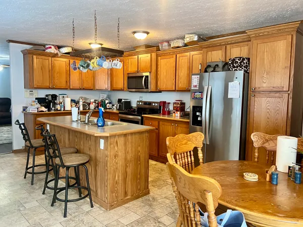 a kitchen with stainless steel appliances granite countertop a refrigerator a sink a stove and chairs